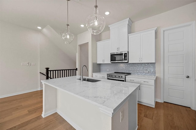 kitchen featuring decorative light fixtures, a kitchen island with sink, sink, and stainless steel appliances