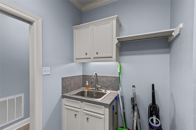 kitchen featuring white cabinetry, crown molding, and sink