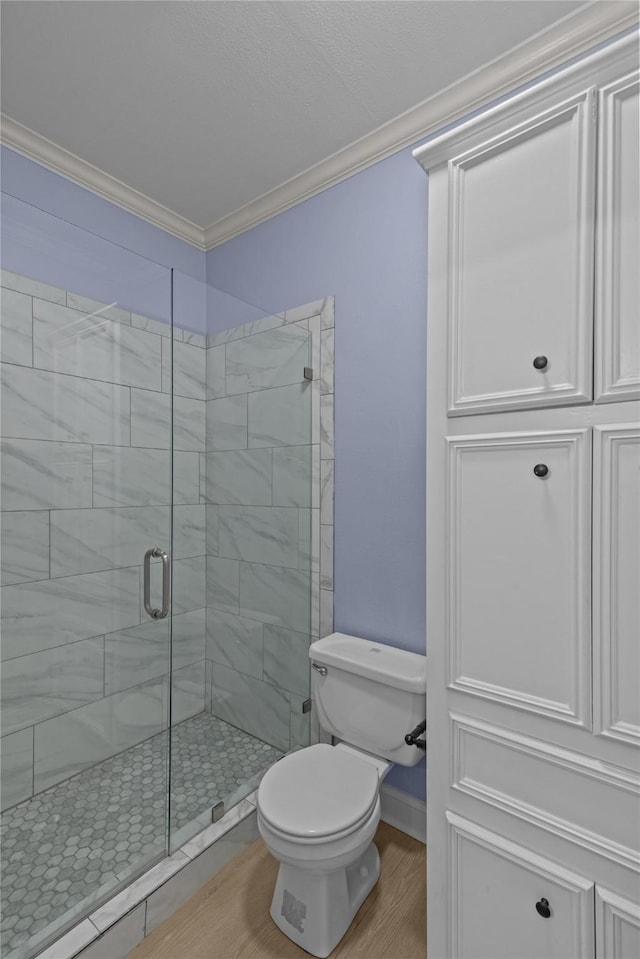 bathroom featuring toilet, wood-type flooring, a shower with door, and crown molding