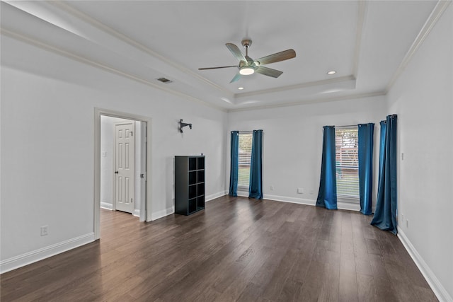 unfurnished room with a raised ceiling, ceiling fan, dark wood-type flooring, and ornamental molding