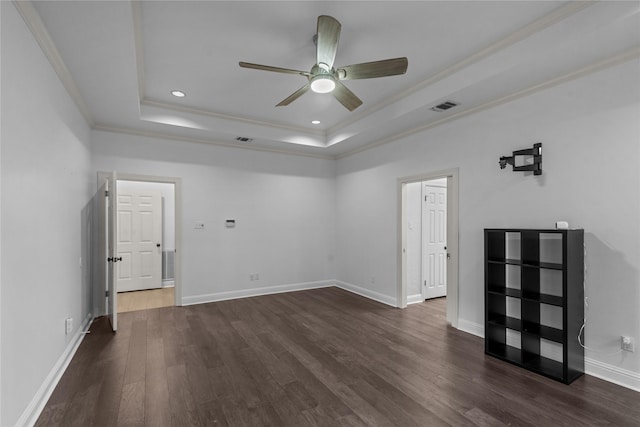 empty room with dark hardwood / wood-style floors, ceiling fan, ornamental molding, and a raised ceiling