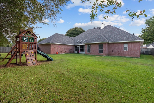 rear view of house featuring a yard and a playground