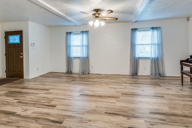 unfurnished living room featuring beam ceiling, wood finished floors, and ceiling fan