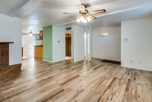 unfurnished living room featuring a ceiling fan, visible vents, and wood finished floors