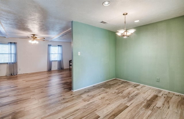 spare room with visible vents, wood finished floors, ceiling fan with notable chandelier, and recessed lighting