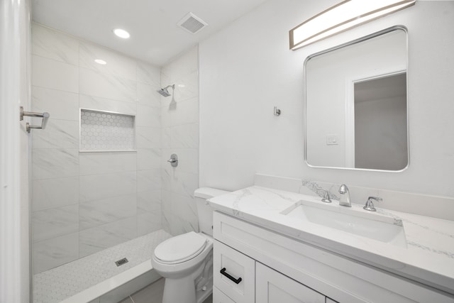 bathroom with toilet, vanity, and tiled shower