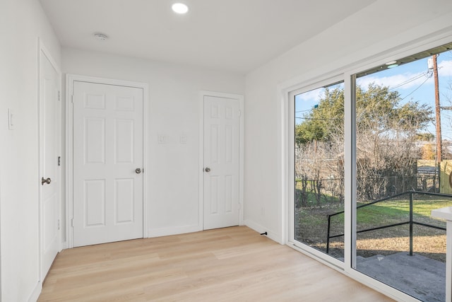 unfurnished bedroom with access to exterior, a closet, and light wood-type flooring