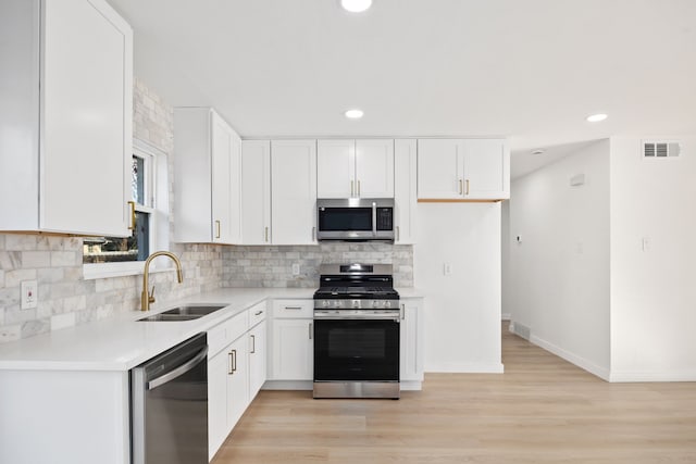 kitchen featuring light wood-type flooring, appliances with stainless steel finishes, white cabinetry, and sink