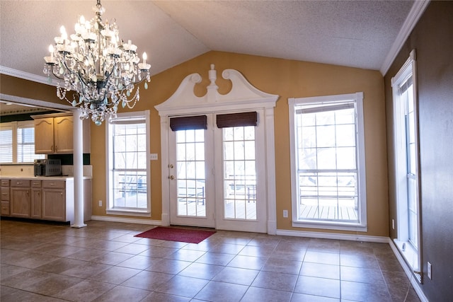 entryway with dark tile patterned floors, vaulted ceiling, a notable chandelier, and a textured ceiling