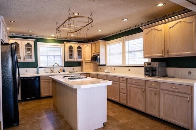 kitchen with light brown cabinetry, tile counters, a center island, and black appliances