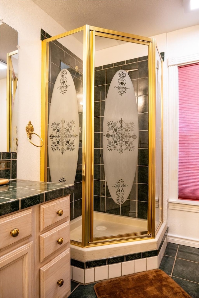 bathroom featuring a shower with shower door, vanity, and tile patterned flooring