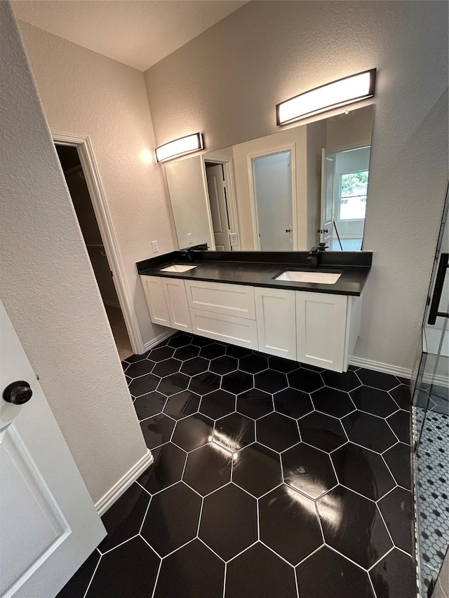 full bathroom with a textured wall, a sink, and double vanity