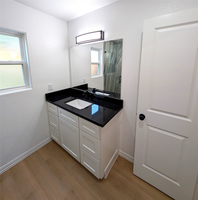 bathroom with a healthy amount of sunlight, wood finished floors, and vanity