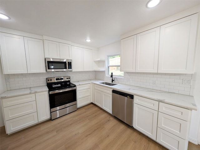 kitchen featuring stainless steel appliances, a sink, white cabinetry, open shelves, and light wood finished floors