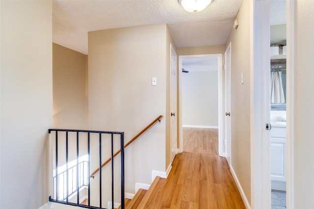 hall with a textured ceiling and light hardwood / wood-style flooring