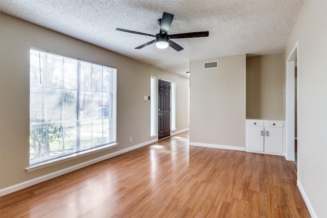 unfurnished room with a textured ceiling, ceiling fan, and light wood-type flooring