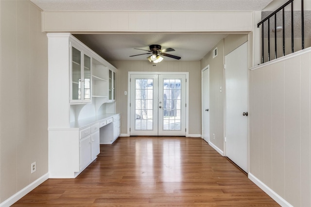 doorway with ceiling fan, hardwood / wood-style floors, built in desk, a textured ceiling, and french doors