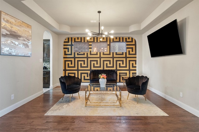 sitting room with a chandelier, a raised ceiling, and hardwood / wood-style floors