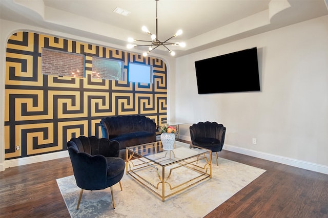 living room with an inviting chandelier, dark hardwood / wood-style floors, and a raised ceiling