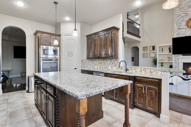 kitchen featuring dark brown cabinetry, decorative light fixtures, stainless steel appliances, and a kitchen island