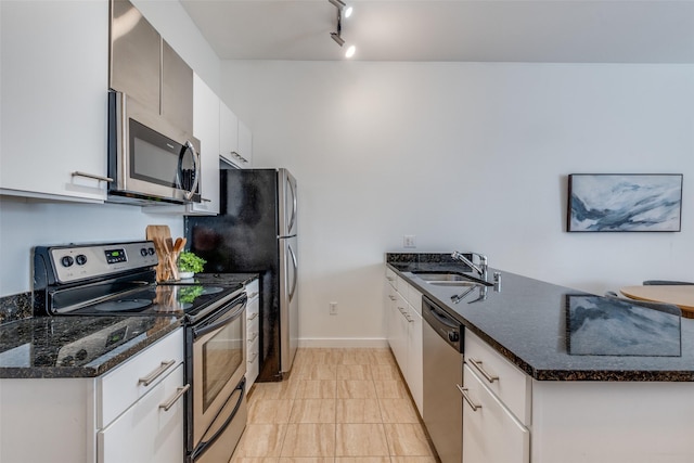 kitchen with white cabinetry, stainless steel appliances, dark stone counters, sink, and light tile patterned floors