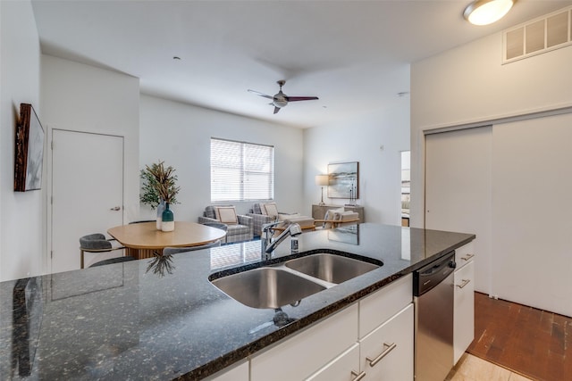 kitchen featuring dark stone countertops, light hardwood / wood-style floors, stainless steel dishwasher, sink, and white cabinetry