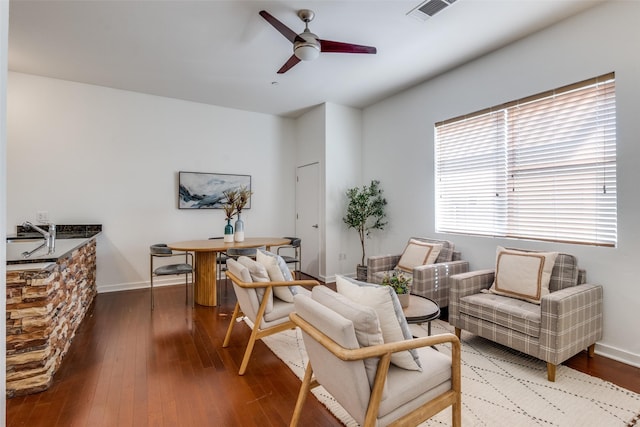 living area featuring ceiling fan and dark hardwood / wood-style flooring