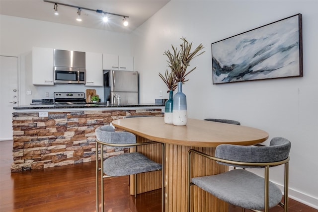 kitchen with dark hardwood / wood-style floors, appliances with stainless steel finishes, and white cabinets