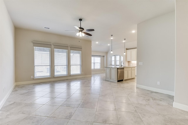 unfurnished living room featuring ceiling fan, light tile patterned floors, and sink