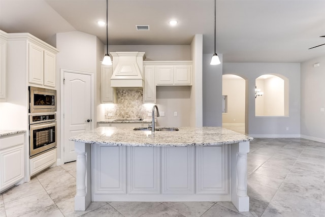 kitchen featuring light stone countertops, stainless steel appliances, custom range hood, and sink