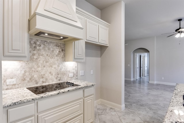 kitchen featuring black electric cooktop, light stone counters, and custom range hood