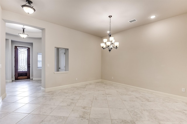 unfurnished room featuring a chandelier