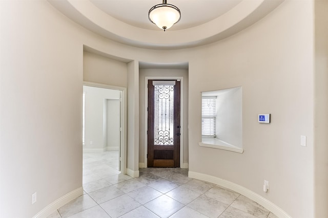 entryway with light tile patterned floors and a raised ceiling