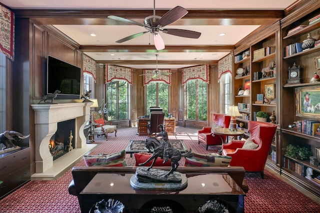 living area with ceiling fan, carpet, built in features, and beamed ceiling