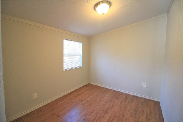 empty room with wood-type flooring and ornamental molding