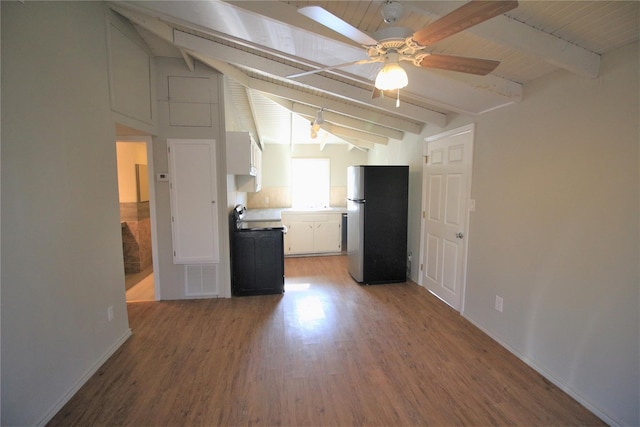 kitchen featuring ceiling fan, hardwood / wood-style floors, lofted ceiling with beams, stainless steel refrigerator, and white cabinetry