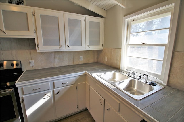 kitchen featuring electric stove, white cabinetry, sink, and tile counters