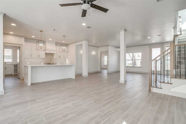 unfurnished living room with ceiling fan, crown molding, light hardwood / wood-style flooring, and sink