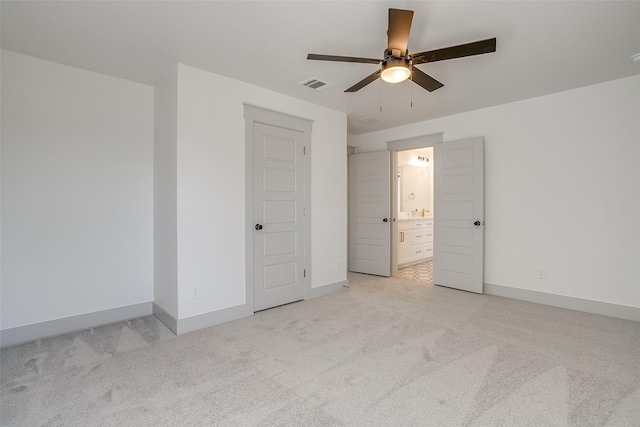 unfurnished bedroom featuring ceiling fan, light colored carpet, a closet, and connected bathroom