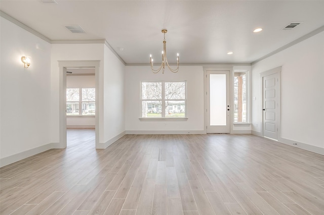 spare room with a notable chandelier, ornamental molding, and light hardwood / wood-style floors