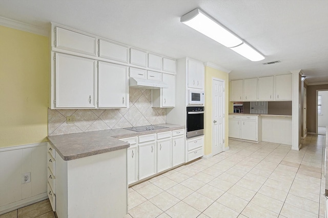 kitchen with white microwave, white cabinetry, ornamental molding, and oven