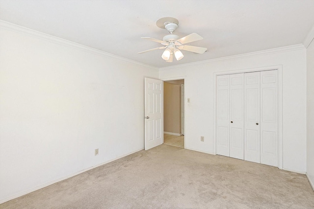 unfurnished bedroom featuring ceiling fan, light colored carpet, a closet, and crown molding