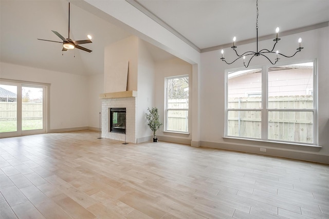 unfurnished living room with ceiling fan with notable chandelier, light hardwood / wood-style flooring, and plenty of natural light