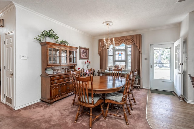 carpeted dining space with a textured ceiling, a chandelier, and ornamental molding