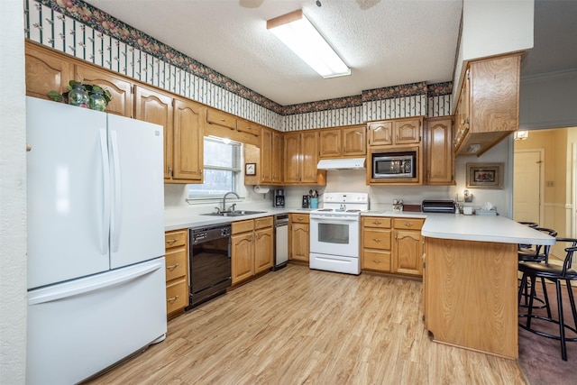 kitchen with white appliances, a textured ceiling, sink, kitchen peninsula, and a breakfast bar