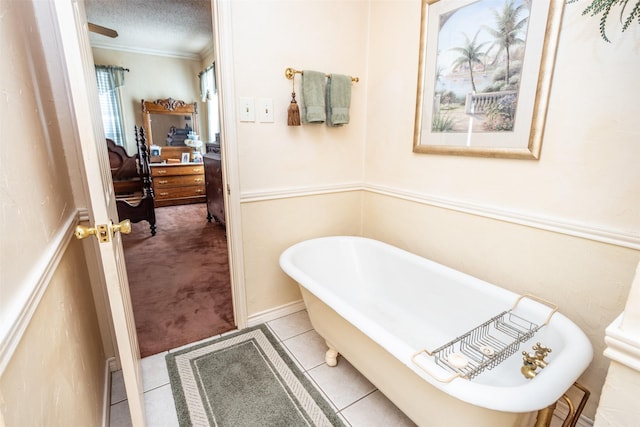 bathroom featuring tile patterned flooring, a tub, crown molding, and a textured ceiling