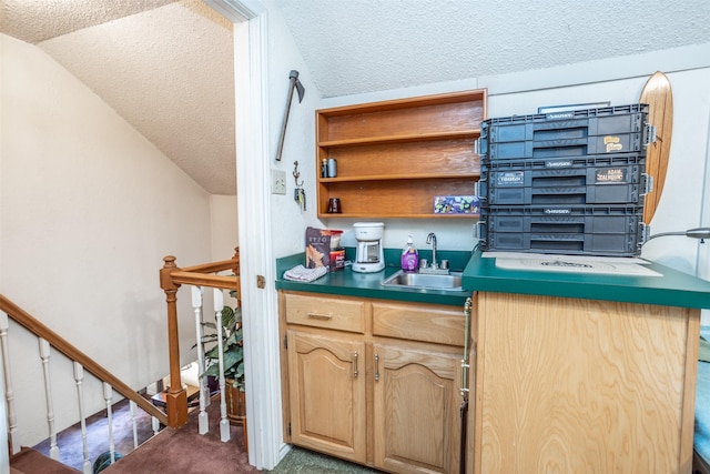 kitchen featuring a textured ceiling, carpet, lofted ceiling, and sink