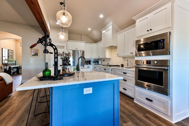 kitchen featuring appliances with stainless steel finishes, a kitchen island with sink, hanging light fixtures, white cabinets, and sink