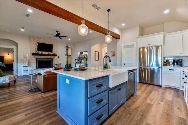 kitchen with white cabinetry, stainless steel appliances, sink, hanging light fixtures, and blue cabinets