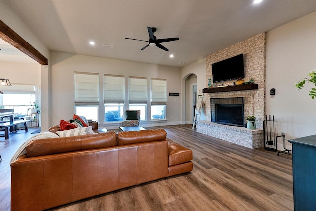 living room featuring a brick fireplace, hardwood / wood-style floors, and ceiling fan